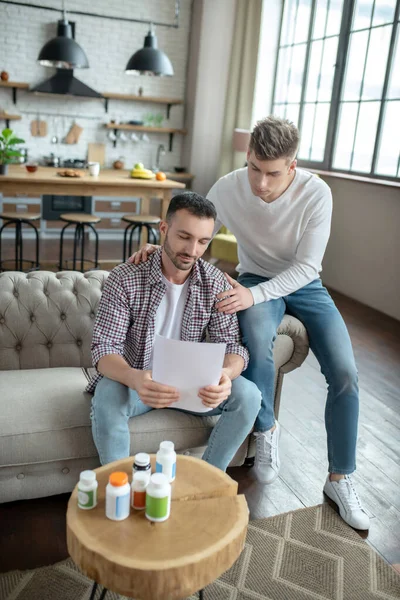 Joven barbudo con una camisa a cuadros sintiéndose infeliz mientras lee los resultados de la prueba — Foto de Stock