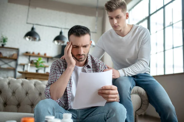 Baard jongeman in een geruite shirt zich ongelukkig voelen over zijn diagnose — Stockfoto