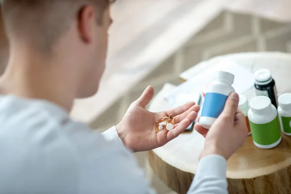 Egy fehér pólós fiatalember, tablettákkal a kezében. — Stock Fotó