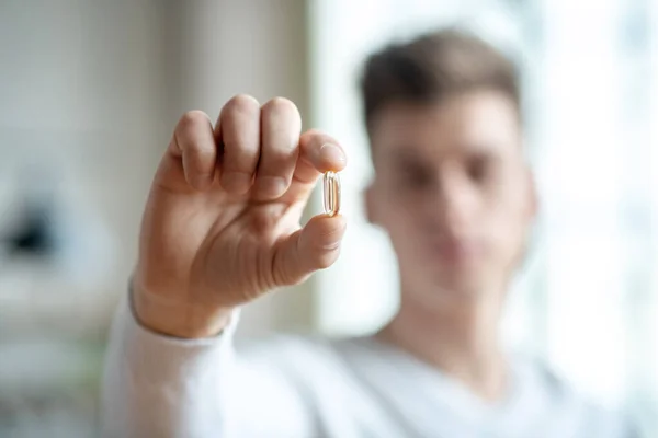 Close up picture of a young man holding a pill — Stock Photo, Image