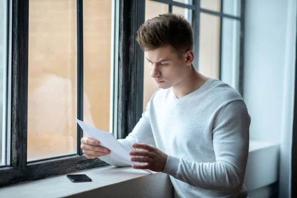 Jongeman in een witte tshirt onderzoeken testresultaten — Stockfoto