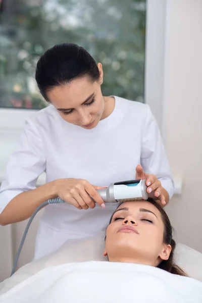 Especialista em massagem vestindo uniforme branco de pé perto do paciente — Fotografia de Stock