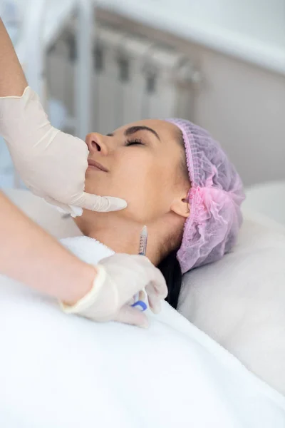 Vrouw die een injectie in de nek krijgt terwijl ze anti-aging procedures ondergaat — Stockfoto