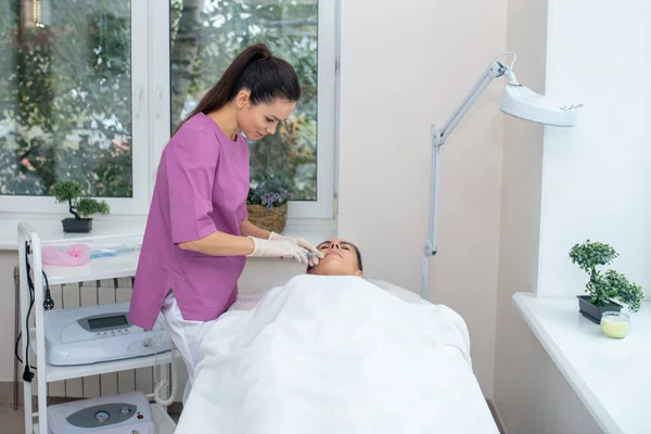 Cosmetólogo vistiendo uniforme morado haciendo inyecciones de belleza — Foto de Stock