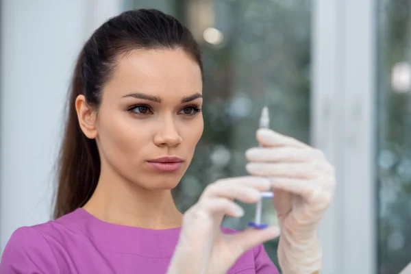 Cosmetologist olhando para a seringa com injeção de beleza — Fotografia de Stock