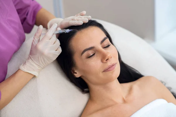 Zakenvrouw sluit ogen terwijl ze mesotherapie injectie krijgt — Stockfoto