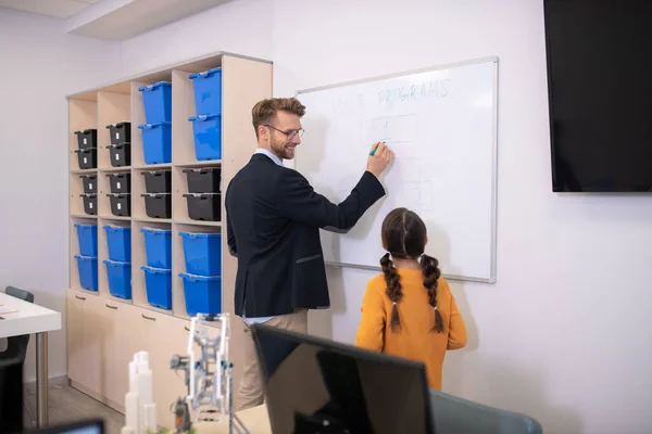 Man leraar schrijven op whiteboard, uitleggen, glimlachen — Stockfoto