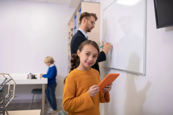 Professor do sexo masculino escrevendo no quadro branco, menina segurando tablet, menino de pé na mesa — Fotografia de Stock