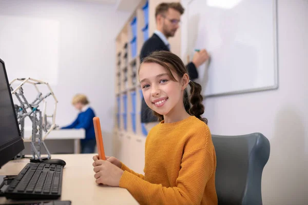 Άντρας δάσκαλος γράφει σε λευκό πίνακα, κορίτσι κάθεται στο γραφείο, αγόρι στέκεται στο παρασκήνιο — Φωτογραφία Αρχείου