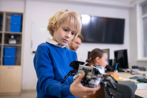 Menino segurando kit de construção, professor e menina no fundo — Fotografia de Stock