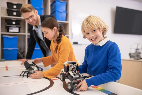 Учні грають з багатофункціональними машинами, хлопчик показує свою посмішку — стокове фото