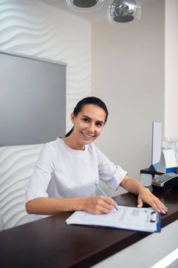Güzellik kliniğinin neşeli müdürü müşterileri karşılarken gülümsüyor.