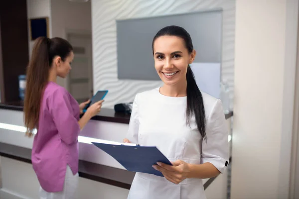 Ung kvinna håller anteckningar när du står nära receptionen — Stockfoto
