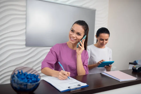 Receptionist of beauty clinic receiving call from client — Stock Photo, Image