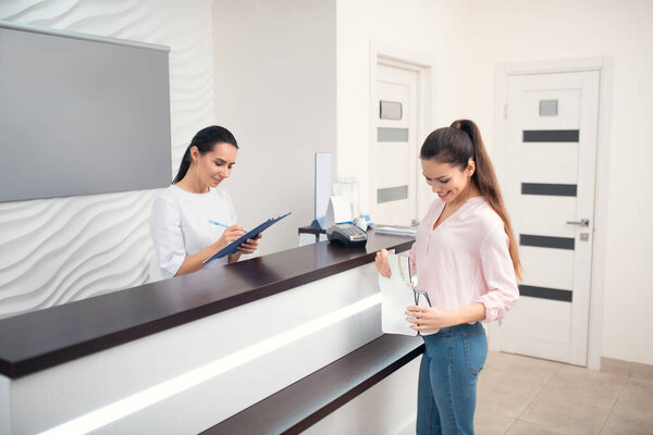 Темноволосая женщина улыбается, когда приходит в знаменитую клинику красоты
