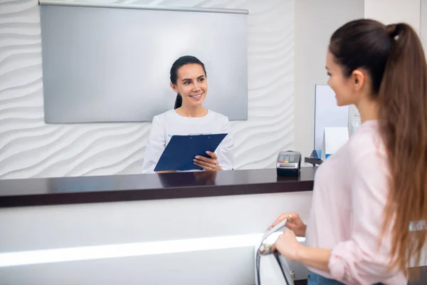 Receptionist talking to client before taking her to cosmetologist