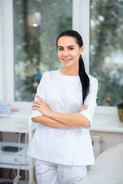 Beautiful cosmetologist wearing white uniform feeling good — Stock Photo, Image