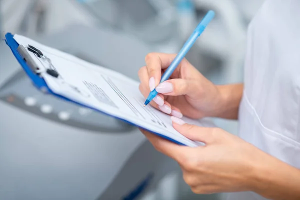 Primer plano de la mujer sosteniendo la pluma mientras toma notas después de ver al cliente — Foto de Stock