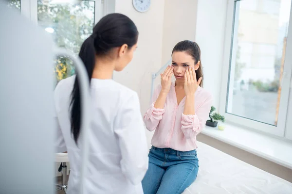 Empresaria contando sobre sus cambios faciales al cirujano plástico — Foto de Stock