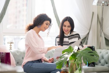 Two dark-haired women choosing beauty treatment and feeling excited