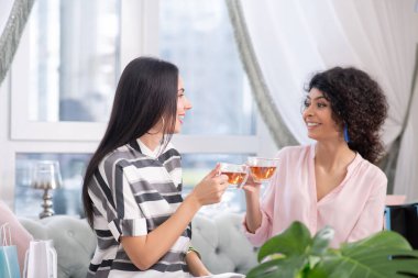 Two dark-haired women having tea and talking