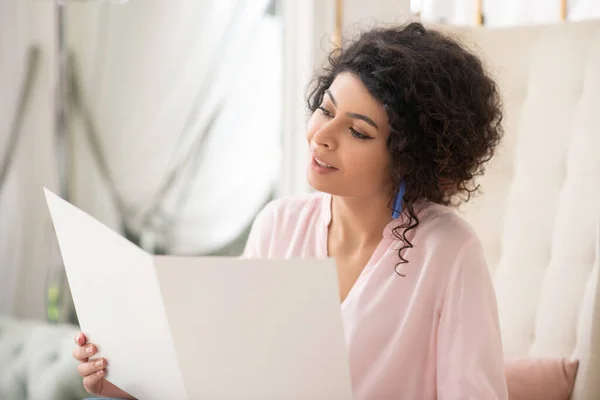 Mujer bastante rizada sosteniendo una lista de precios en sus manos — Foto de Stock