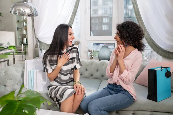 Two dark-haired women talking while sitting on the sofa — Stok fotoğraf