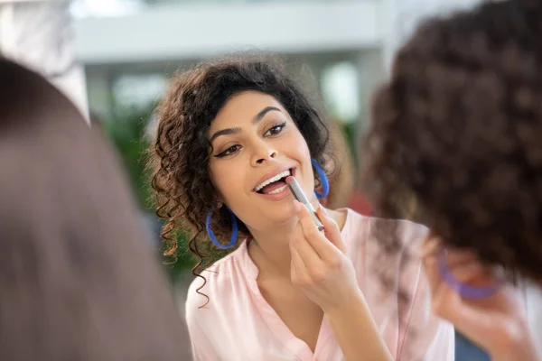 Dark-haired woman putting lipstick on her lips — Stockfoto