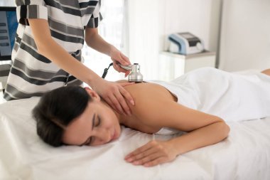 Cosmetologist in striped dress doing beauty procedures to the woman