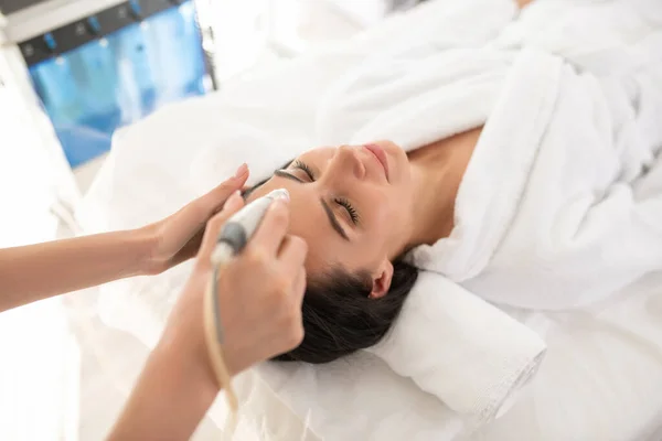 Dark-haired woman laying on the couch having rejuvenation procedures — Stok fotoğraf