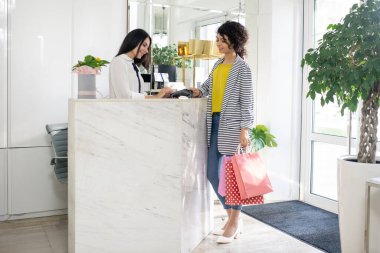 Dark-haired female customer lmaking payment in the store
