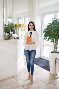 Dark-haired beauty consultant in a white blouse standing in the store