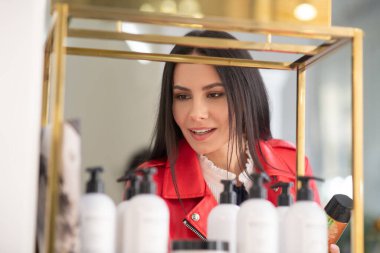 Dark-haired woman looking at body care products
