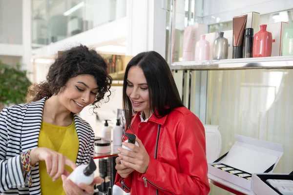 Two beaming ladies choosing hair care products — Stok fotoğraf