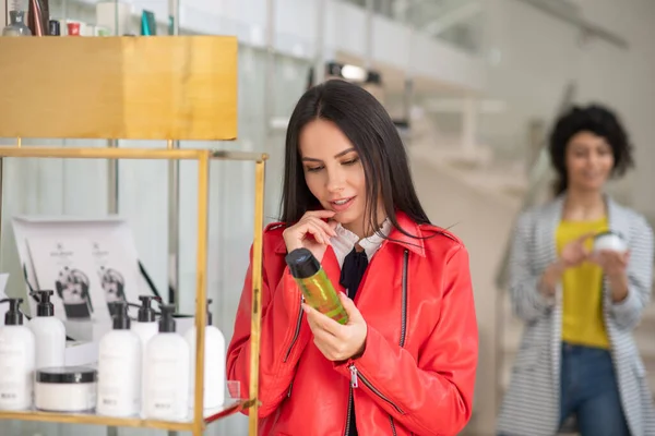 Dark-haired woman with a shower gel in hand looking thoughtful — 스톡 사진