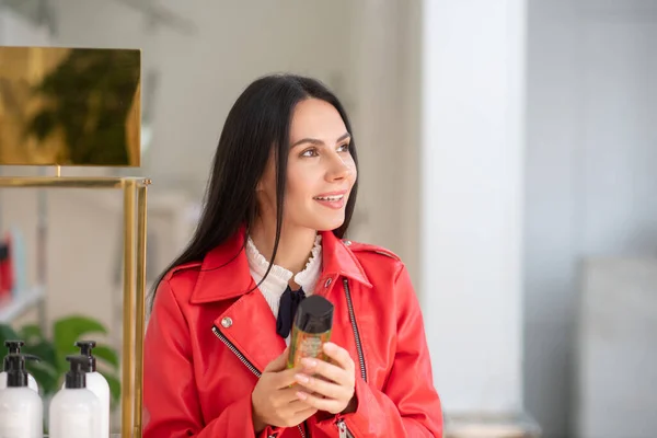 Brunette woman in a red jacket looking dreamy — стокове фото