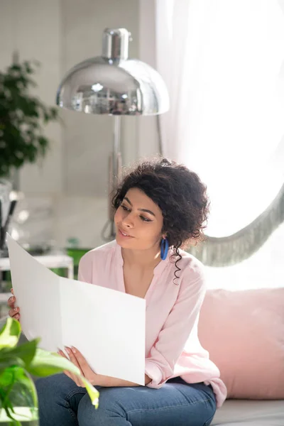 Beautiful curly-haired woman looking trough the price list and looking interested — Stockfoto