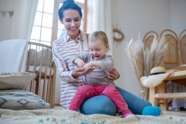 Young mom and daughter playing with artificial stones, smiling happily