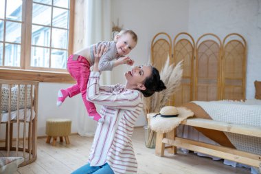 Young mom lifting her daughter, smiling happily