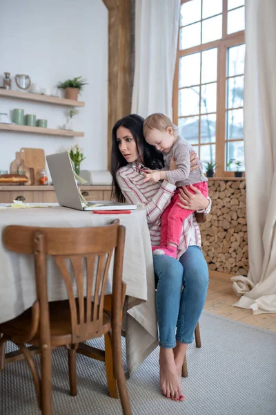 Young mom working, distracted by daughter, feeling upset