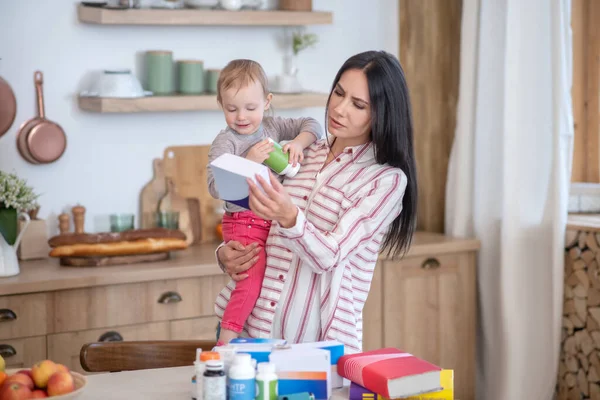 Mom standing, holding her daughter, reading medicine instruction — Stockfoto