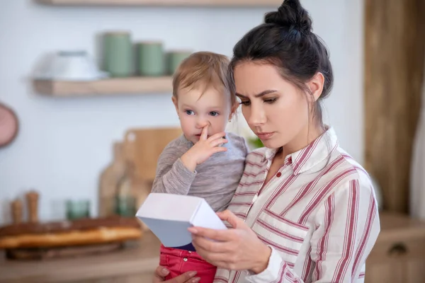 Mom reading medicine instruction, daughter poking nose — Stockfoto