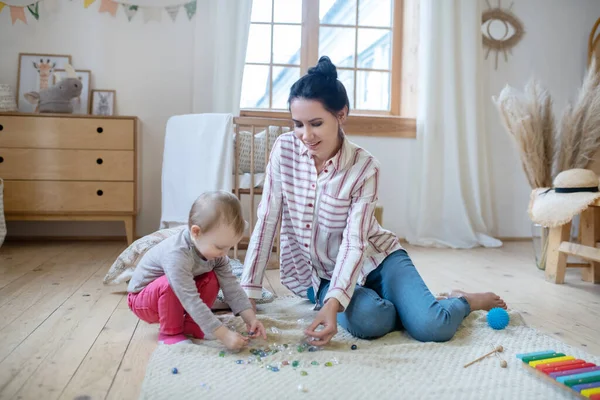 Young mom and daughter playing with artificial stones on the floor — Stockfoto