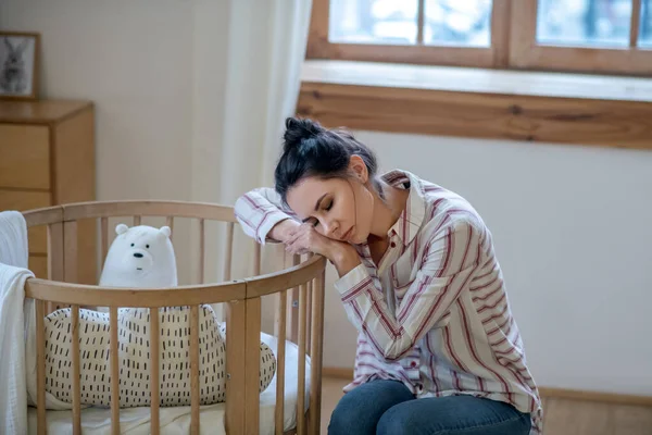 Sonnolenta e stanca mamma riposa la testa sul lettino — Foto Stock