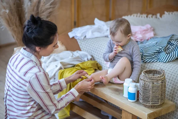 Young mother applying plaster on daughters knee — Stock Photo, Image