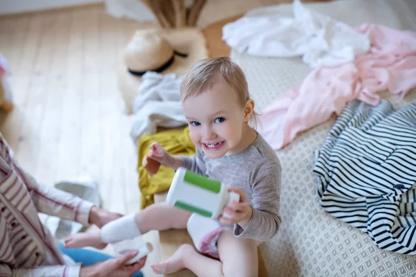 Baby holding medicine bottle with bandage on her leg, smiling — Stock Photo, Image