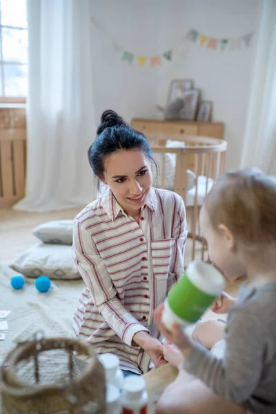 Mom applying bandage on childs leg, girl holding bottle — Stockfoto