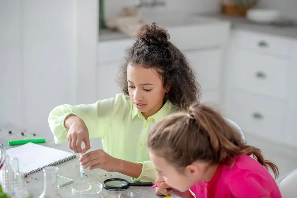 Zwei Mädchen sitzen am Tisch und führen ein Experiment durch. — Stockfoto