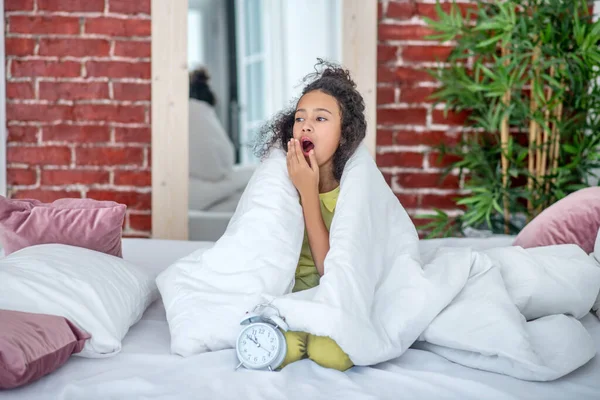 Adolescente sentada sob as capas na cama . — Fotografia de Stock