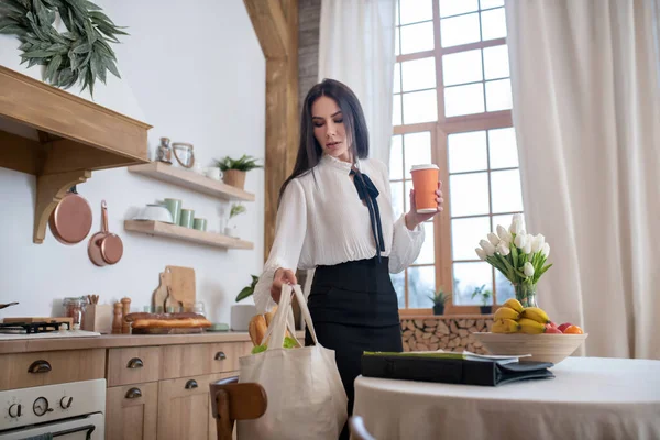 Mujer joven llega a casa después del trabajo con bolsa de compras —  Fotos de Stock